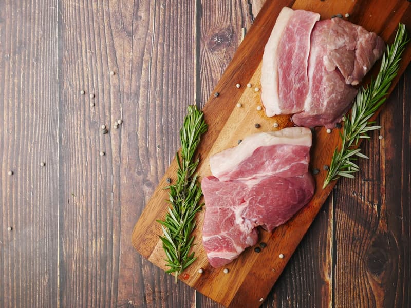 Raw pork loin cuts on a wooden board